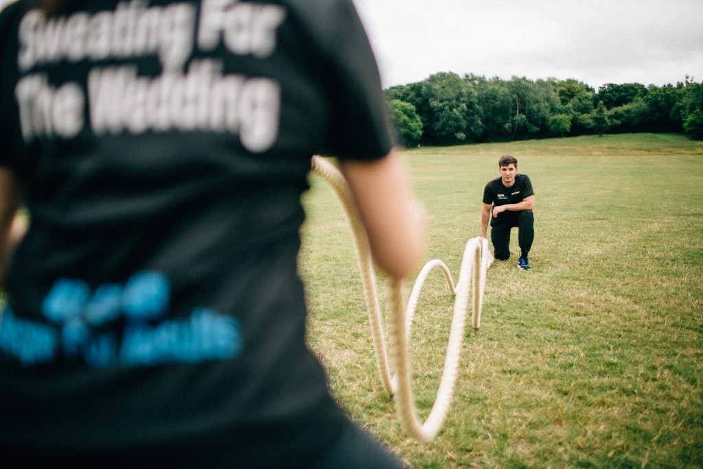 Client using battle ropes while the personal trainer provides encouragement during an outdoor fitness session.